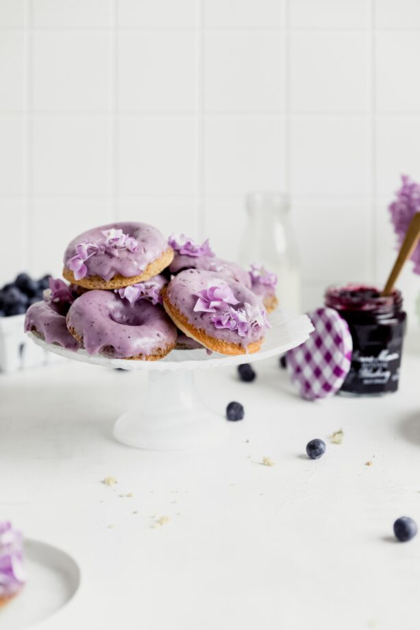 baked blueberry donuts with blueberry frosting on a cake stand