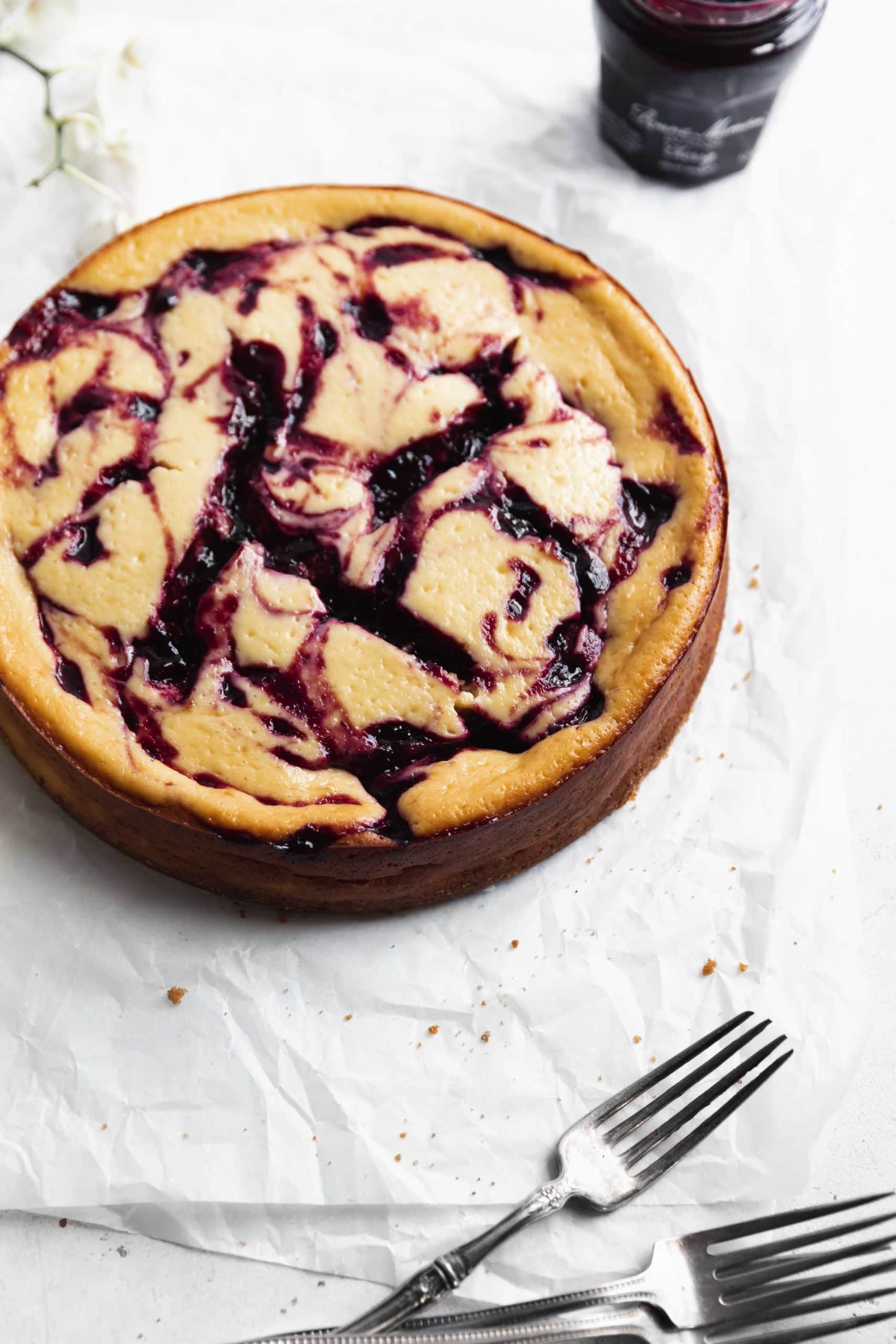 close up shot of cherry swirled cheesecake with three forks