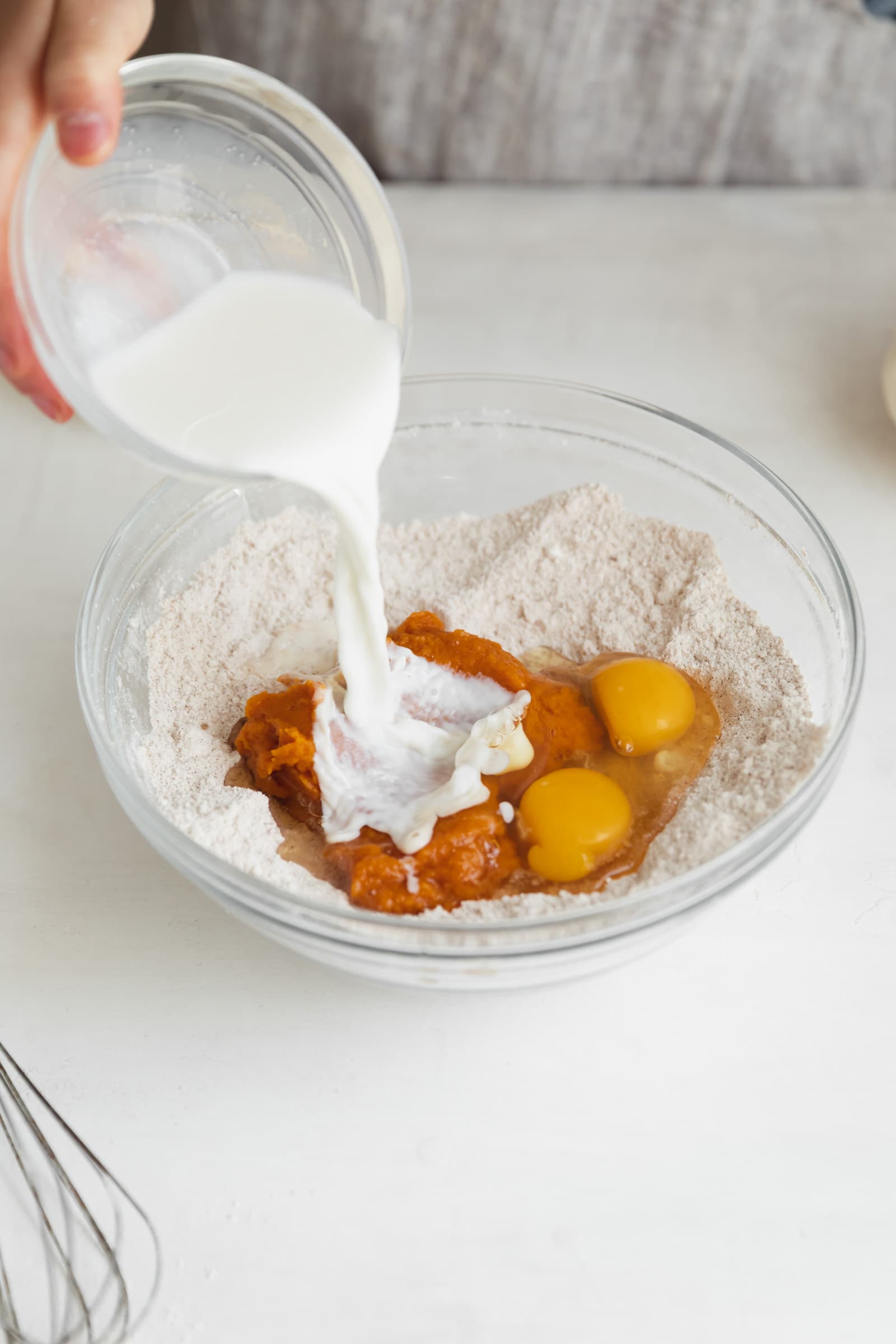 milk pouring into bowl of pumpkin batter